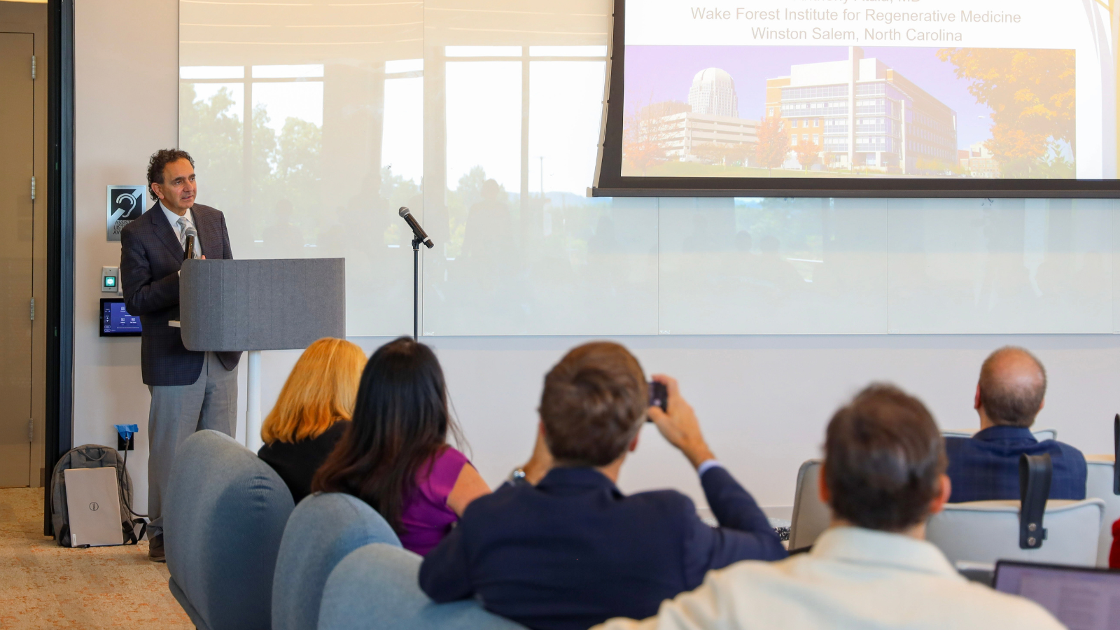 Anthony Atala presents during the symposium, with a slide featuring the Wake Forest Institute for Regenerative Medicine projected behind him.