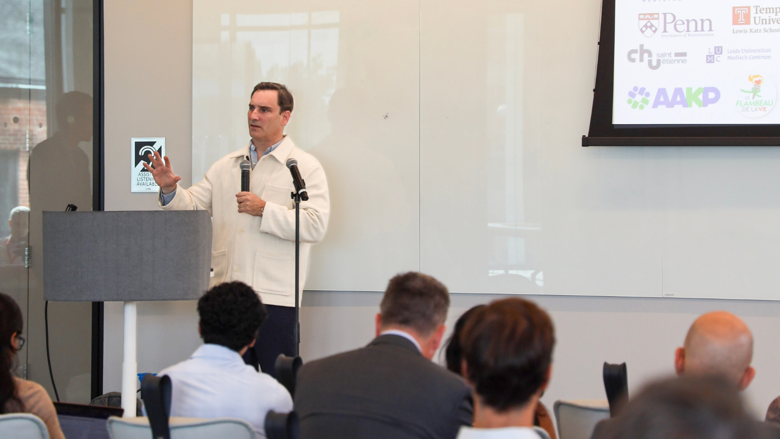 Alexandre Loupy addresses symposium attendees with a handheld microphone during his presentation on transplantation research