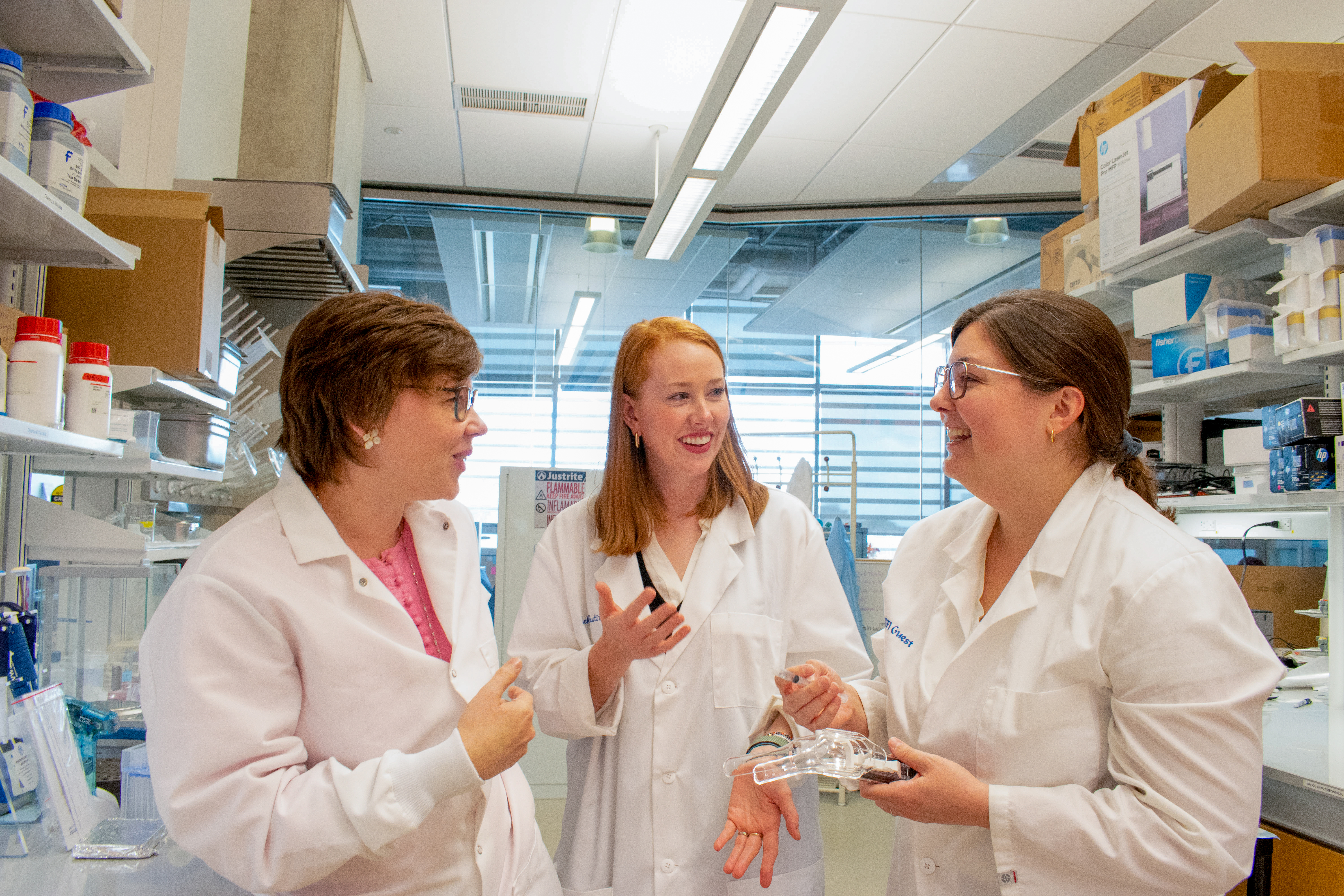 Katharina Maisel, BIOE associate professor, stands on the left, Hannah Zierden of the Fischell Institute stands in the center, and Jenna Mueller, BIOE associate professor, stands on the right as they talk in a laboratory.