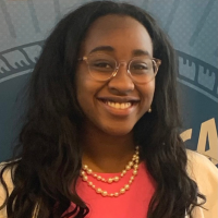 Lauren smiling at the camera while wearing glasses and a pink top