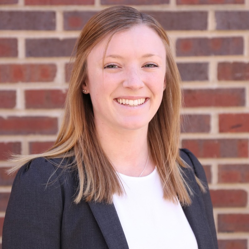 Headshot of Callie Weber, photographed in front of a brick background