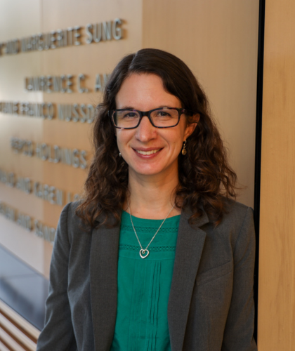 Deborah Goldberg smiling at the camera in front of clark hall donor wall