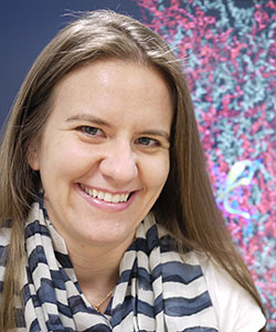 Dr. Silvina Matysiak pictured in front of a screen displaying protein structures