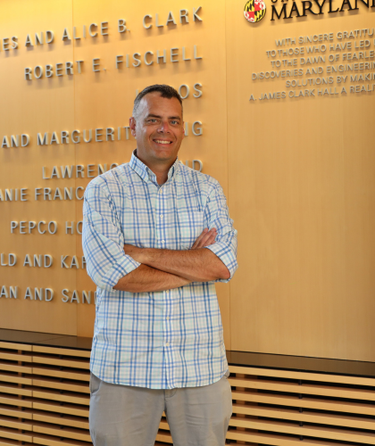 Steven standing with his arms crossed in front of a University of Maryland donor wall