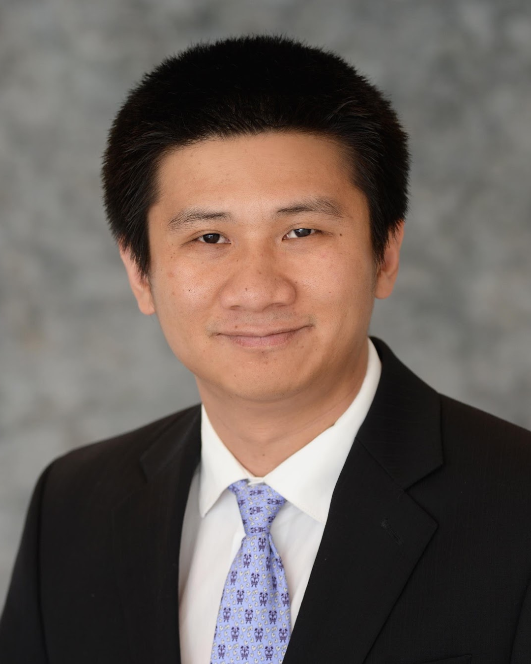 Professional headshot of Yu Gan wearing a black suit, white dress shirt